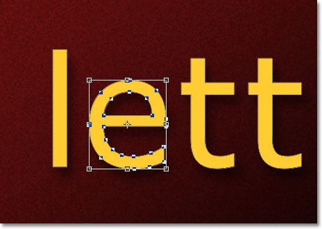 The Free Transform bounding box and handles appears around the letter. Image &copy; 2011 Photoshop Essentials.com.