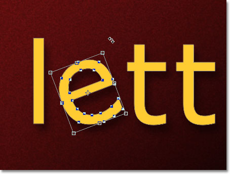 The Free Transform bounding box and handles appears around the letter. Image &copy; 2011 Photoshop Essentials.com.